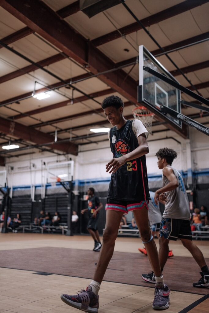 Player walking on the court during warmups in an indoor gym.