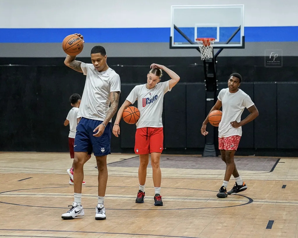Basketball players practicing ball-handling drills on an indoor court.